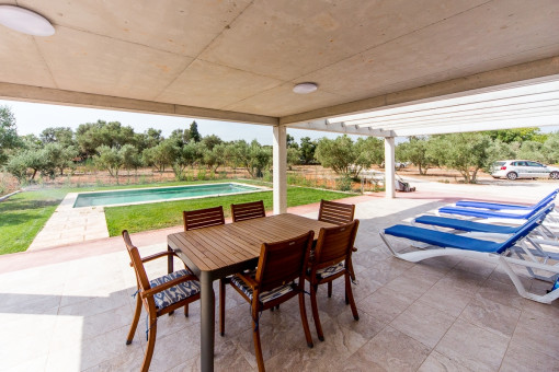 Terraza cubierta con mesa y vistas al jardín